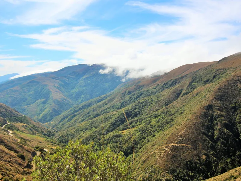 Clouds drifting above green mountain slopes in the Manu region.
